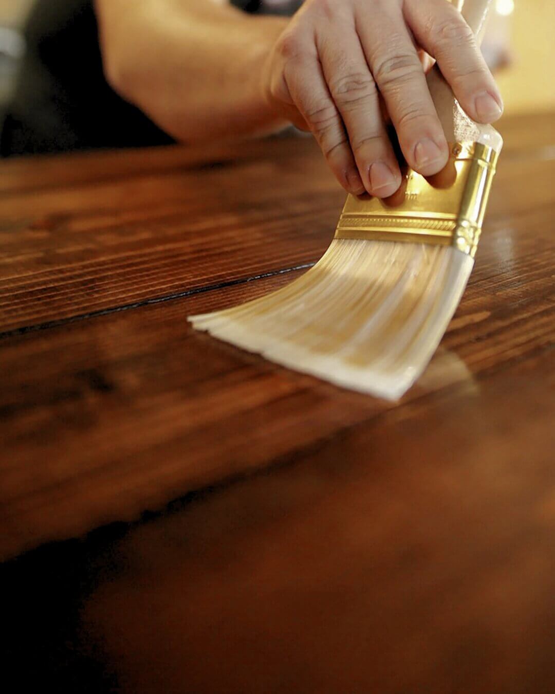 Processo di applicazione di una finitura con pennello su un mobile in legno antico